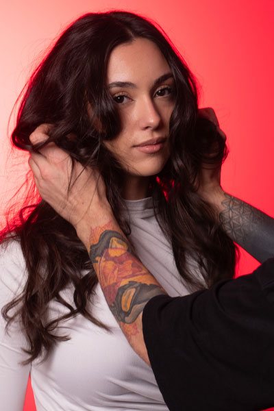 Modella con capelli lunghi mossi su sfondo rosso durante uno shooting